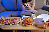 Young asian woman takeaway eating junk food unhealthy on couch watching tv series eatery fast food and drinking in living room enjoy happiness at home.