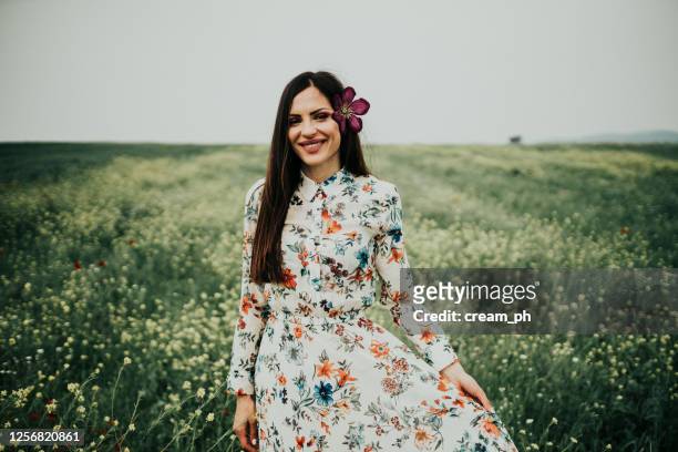 woman with flower in hair enjoying sunny day in the flower field - floral dress stock pictures, royalty-free photos & images