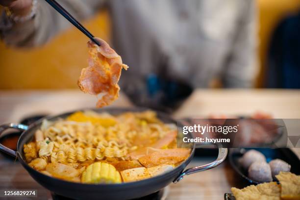 young asian woman eating korean dish, army stew (budae jjigae) in restaurant - hot pots stock pictures, royalty-free photos & images