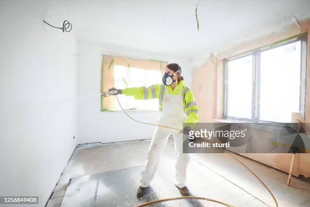 female painter using spray gun - spray paint stock pictures, royalty-free photos & images