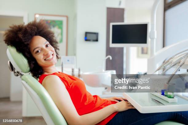 porträt einer jungen afroamerikanerin, die einen zahnarzt besucht - zahnarztstuhl stock-fotos und bilder