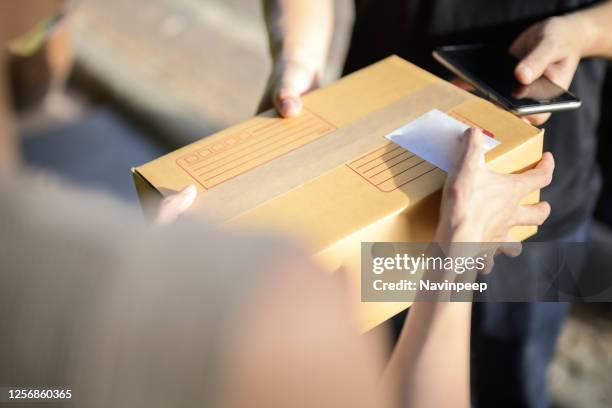 digital delivery, delivering and receiving cardboard box package, with mobile phone in hand - 配達員 ストックフォトと画像