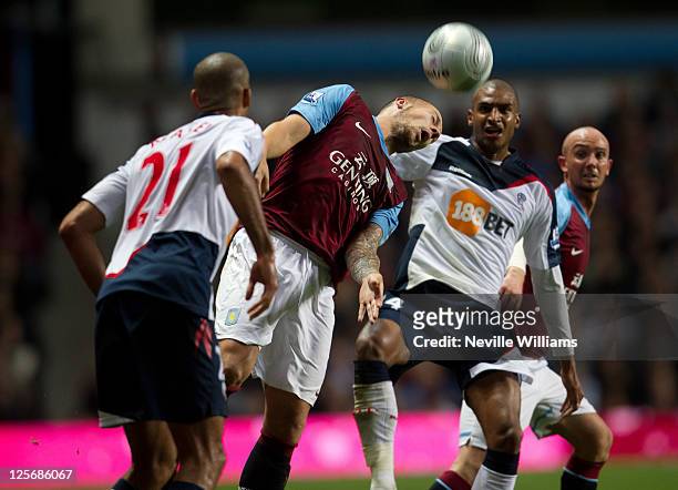 Alan Hutton of Aston Villa challenged by David Ngog of Bolton Wanderers during the Carling Cup third round match between Aston Villa and Bolton...