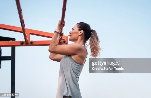 fit woman doing pull ups on a bodyweight street workout - horizontal bar stock pictures, royalty-free photos & images