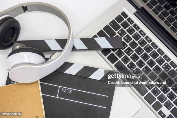 office stuff with movie clapper laptop and coffee cup pen notepad on the wood table top view shot.dark effect - scriptwriter fotografías e imágenes de stock