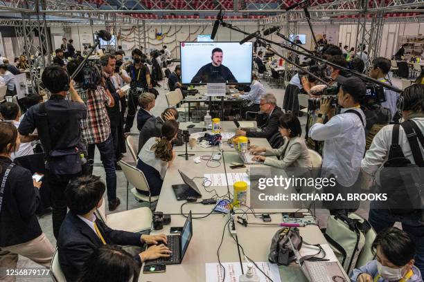 Members of the media gather around a television at the international media centre to listen to the press conference by Ukraine's President Volodymyr...