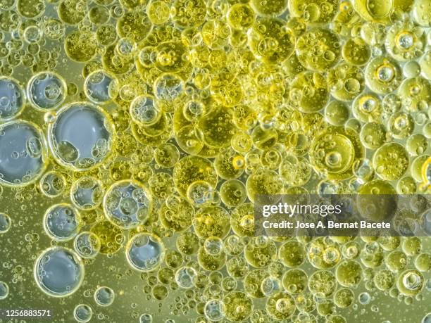 full frame of abstract shapes and textures formed of bubbles and drops on a yellow color liquid background. - oil splashing stock pictures, royalty-free photos & images