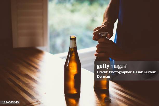 a man opening the cap of the beer bottle with a bottle opener - beer cap stock pictures, royalty-free photos & images