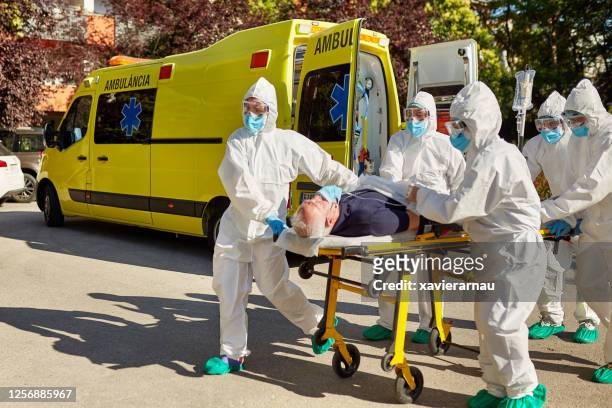 doctors in protective suits moving patient from ambulance - covid 19 stock pictures, royalty-free photos & images