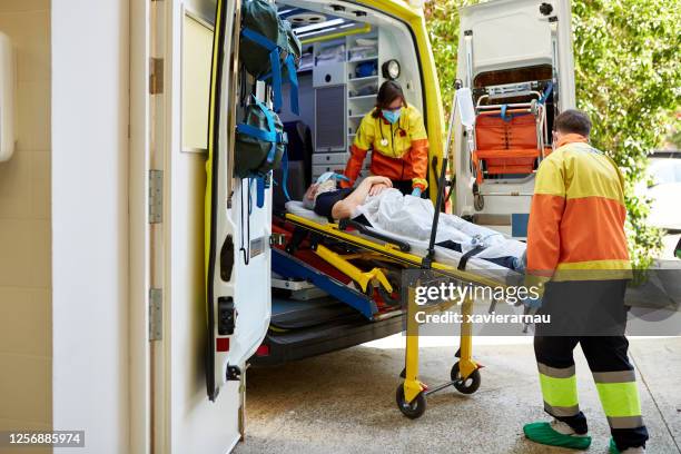 ambulanzpersonal verlegt senior man auf stretcher ins krankenhaus - stretcher stock-fotos und bilder