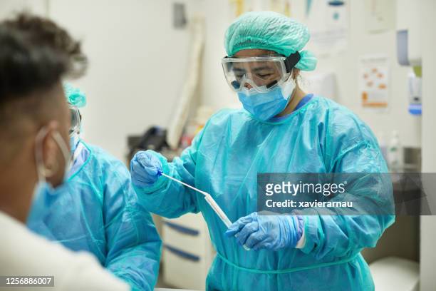 hospital nurse placing test swab in transport medium - protective workwear stock pictures, royalty-free photos & images