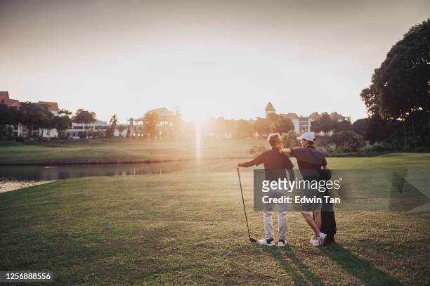 an asian chinese senior man golfer carrying his golf club on his shoulder and looking at the view in golf course - golf stock pictures, royalty-free photos & images