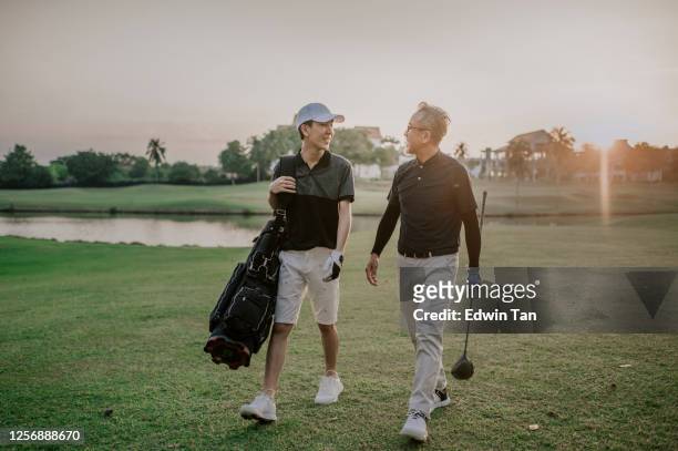 an asian chinese senior man golfer walking and talking to his son who carrying golf bag at the end of the game happily in melaka golf course - father son golf stock pictures, royalty-free photos & images