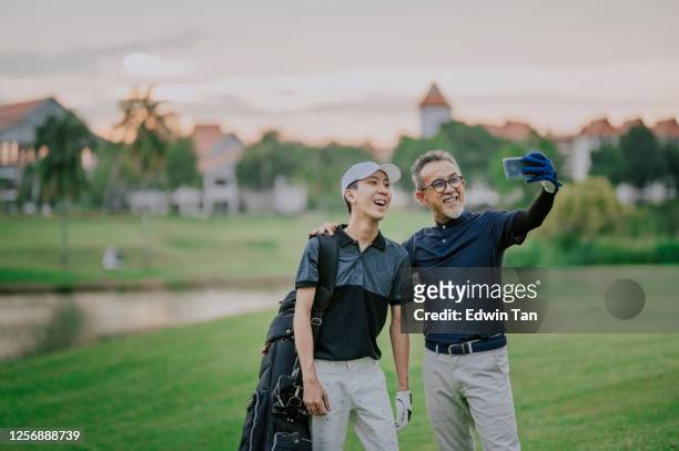 een aziatische chinese hogere mensgolfer die selfie met zijn zoon na het winnen van het golfspel met toothy glimlach heeft - malaysia father and son stockfoto's en -beelden