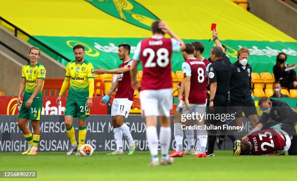 Josip Drmic of Norwich City is shown a red card by Match Referee, Kevin Friend as Erik Pieters of Burnley receives medical treatment during the...