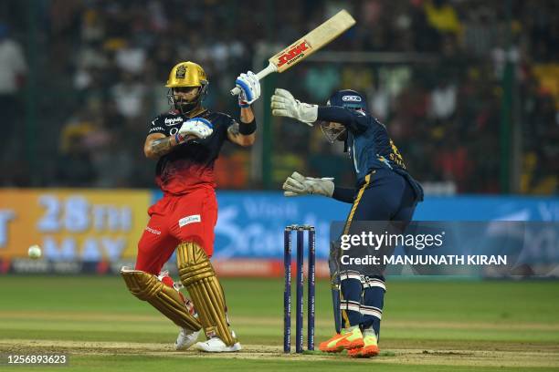 Royal Challengers Bangalore's Virat Kohli plays a shot as Gujarat Titans' wicketkeeper Wriddhiman Saha reacts during the Indian Premier League...