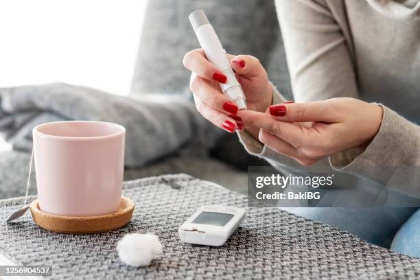 mittlere erwachsene diabetikerin bei der überprüfung des glukosespiegels zu hause - blutzuckermessung stock-fotos und bilder