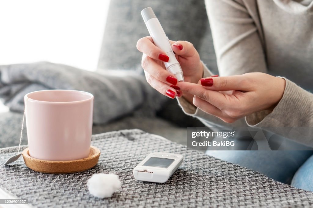 Mid adult diabetic woman checking glucose level at home