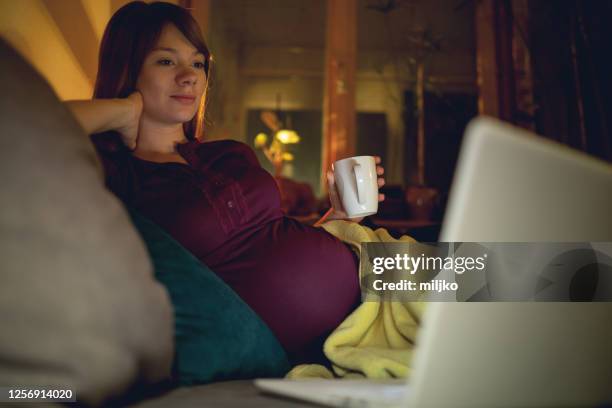 schöne schwangere frau schaut film - family on couch with mugs stock-fotos und bilder