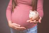 Pregnant woman with piggy bank, saving money to her newborn baby. Money saving, donation, economizing, pregnancy, finance, investment, fund and life insurance concept