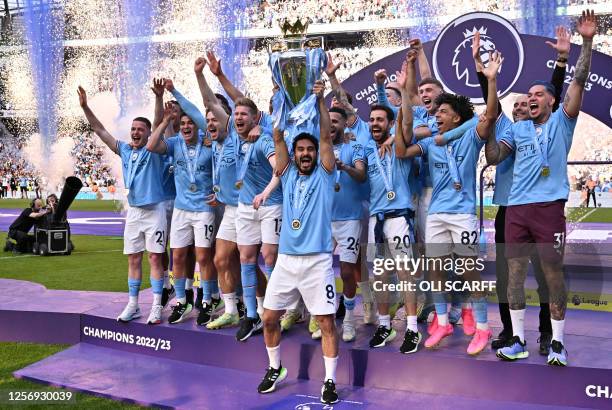 Manchester City's German midfielder Ilkay Gundogan lifts the trophy as Manchester City players celebrate winning the title at the presentation...