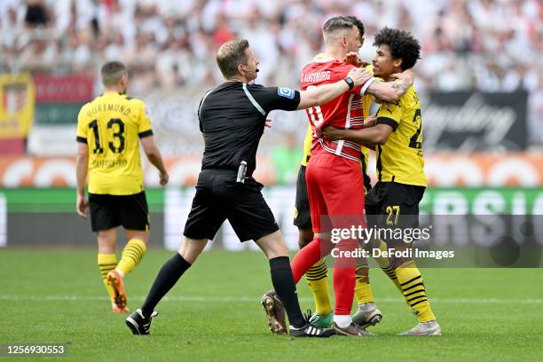 Referee Tobias Welz, Jeffrey Gouweleeuw of FC Augsburg and Karim Adeyemi of Borussia Dortmund gestures during the Bundesliga match between FC...