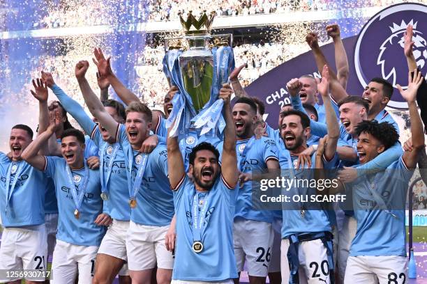 Manchester City's German midfielder Ilkay Gundogan lifts the trophy as Manchester City players celebrate winning the title at the presentation...