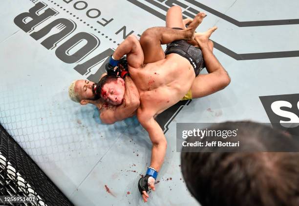 Deiveson Figueiredo of Brazil secures a rear choke submission against Joseph Benavidez in their UFC flyweight championship bout during the UFC Fight...