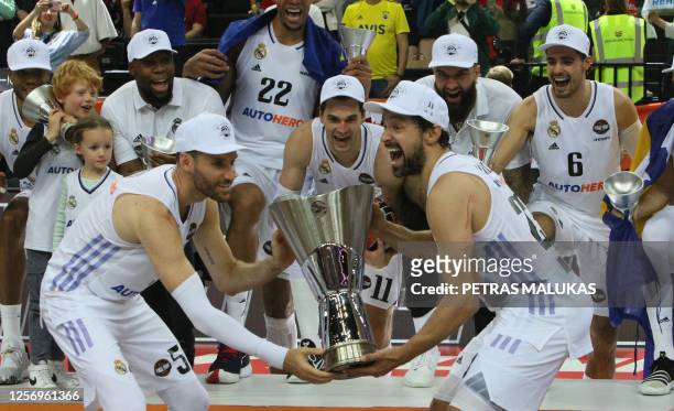 Real Madrid's Spanish Guard Sergio Llull and his Spanish teammate Rudy Fernandez raise the trophy with their teammates and some family members after...