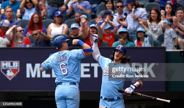 Josh Jung of the Texas Rangers celebrates with teammate Jonah Heim after hitting a home run against the Colorado Rockies during the second inning at...