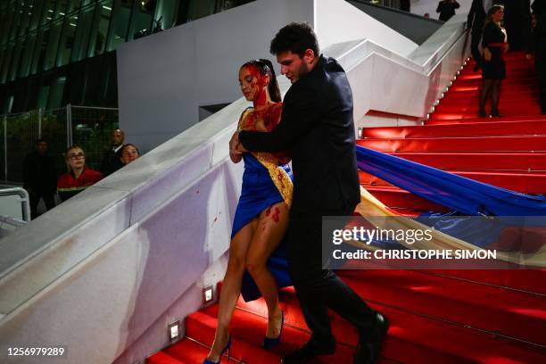 Ukrainian influencer Ilona Chernobai, wearing a dress in the colours of the Ukrainian flag, is detained by security after she covered herself in fake...