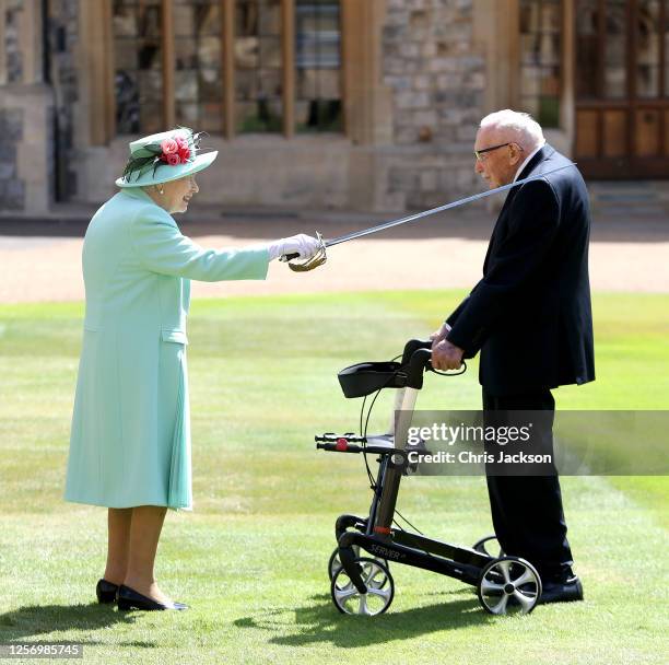 Queen Elizabeth II awards Captain Sir Thomas Moore with the insignia of Knight Bachelor at Windsor Castle on July 17, 2020 in Windsor, England....