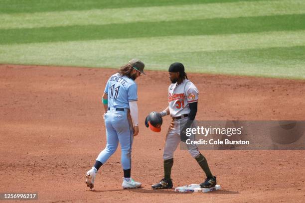 Cedric Mullins of the Baltimore Orioles picks up his helmet in front of Bo Bichette of the Toronto Blue Jays after he steals second base in the third...