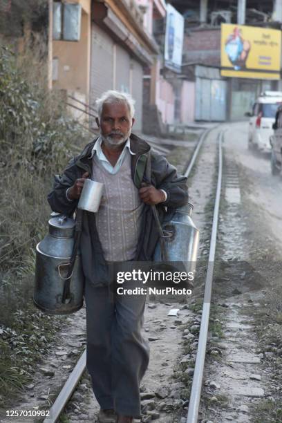 Milkman carries home his empty containers as he walks along the tracks of the Toy Train in Darjeeling, West Bengal, India.