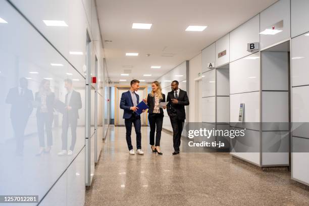 business people walking in a corridor of a business building - free trade hall stock pictures, royalty-free photos & images