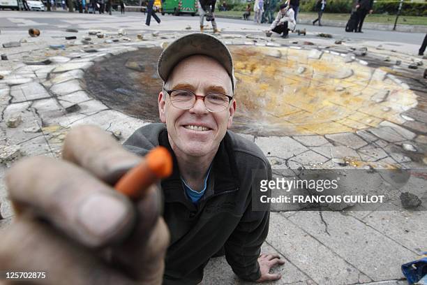 British artist specialized in pavement drawings, wall murals and realistic paintings, Julian Beever, poses next to his pavement painting of a crater...