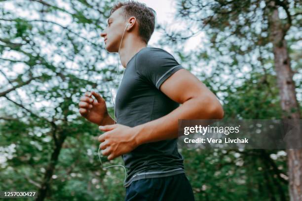portrait of a sporty young man running outdoors in nature - human body part stock pictures, royalty-free photos & images