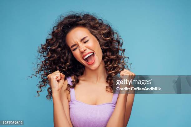 girl on a blue background rejoices at her success - happiness imagens e fotografias de stock