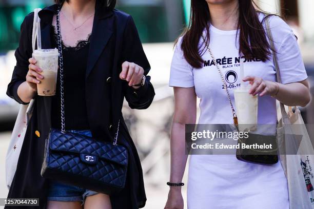 Passerby wears a black jacket, a black top with embroidery, a Chanel quilted bag, holds a cold mocaccino drink ; a guest wears a white "Maree Noire"...