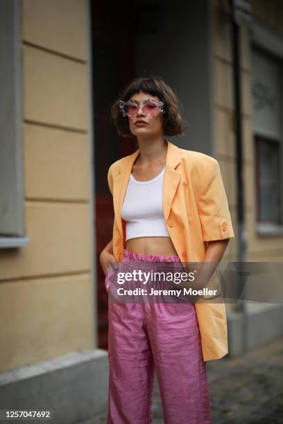 Lea Neumann wearing Komono shades, Stine Goya pants, vintage orange blazer, Urban Outfitters top on July 15, 2020 in Berlin, Germany.