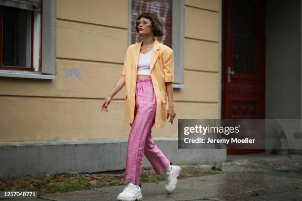 Lea Neumann wearing Komono shades, Stine Goya pants, vintage orange blazer, Urban Outfitters top and Eytys sneaker on July 15, 2020 in Berlin,...