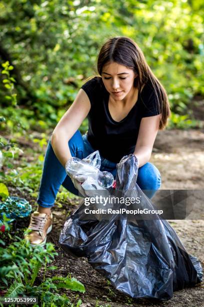 woman pick up bottle from ground, use garbage bag for collecting plastic wastes. environmental pollution. eco friendly. plastic recycle. trash management. cleaning area park ,volunteer concept - picking up garbage stock pictures, royalty-free photos & images