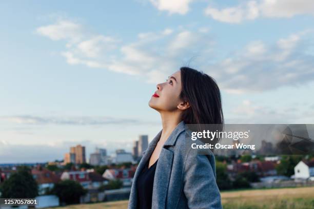 young lady embracing hope and freedom - woman looking up sideview stock-fotos und bilder