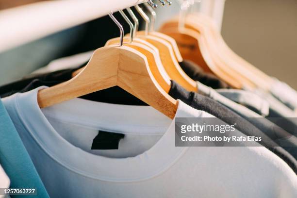 t-shirts on hangers - coat hanger stock-fotos und bilder