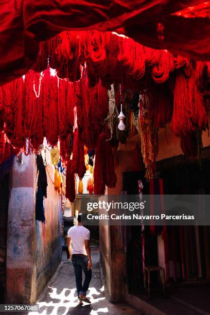 vertical photo of dyed silk threads hanging in the narrow streets of a morocco souk - marrakesh imagens e fotografias de stock