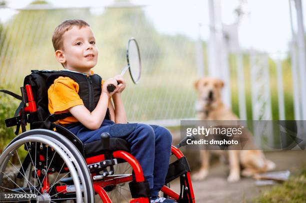behinderter junge mit badmintonschläger - child in wheelchair stock-fotos und bilder
