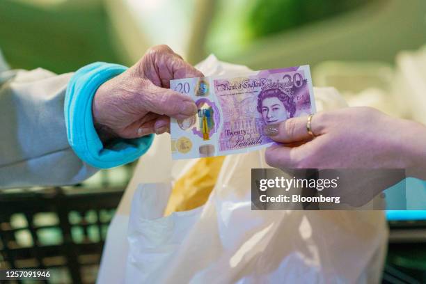 Shopper pays for groceries using a 20-pound banknote at an indoor market in Sheffield, UK, on Friday, May 19, 2023. The Office for National...