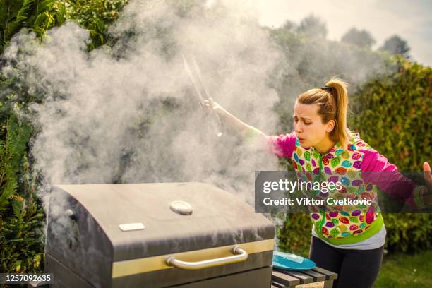 vrouw die voedsel op een barbecue in binnenplaats brandt - backyard grilling stockfoto's en -beelden