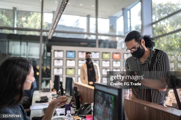 receptionist register employee while he's washing hands with alcohol sanitizer in the entrance of office's lobby - with face mask - covid greeting stock pictures, royalty-free photos & images