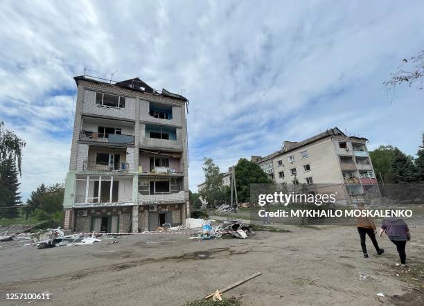 People walk past a damaged residential building following a Russian strike in a small town in the Dnipropetrovsk region on May 22 amid the Russian...